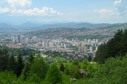 Panoramski pogled na gradski pejzaž Sarajeva smješten u dolini okruženoj planinama.