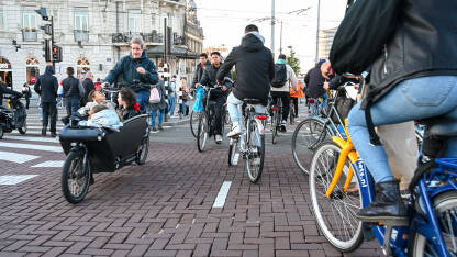 Amsterdam, Nizozemska: Grupa biciklista vozi bicikle po ulici. Biciklizam u  gradu. Ljudi koriste bicikle za vožnju.