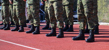 Formacija vojnika u maskirnim hlačama  i crnim borbenim čizmama stoji u redu tokom vojne vježbe. Red vojnika odjevenog u taktičke maskirne uniforme. Vojska u uniformi.