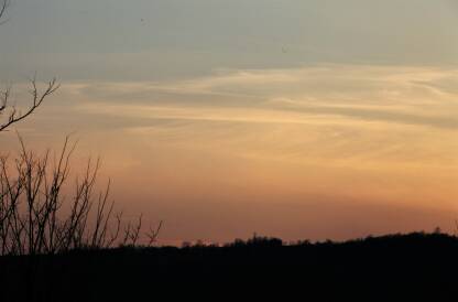 Pejzaz zalaska sunca, narandzasto nebo sa plavim nijansama, priroda u crnoj boji donjeg dela fotografije