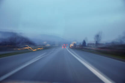 Zamućena fotografija vožnje autoputem u zoru. Zamućeni pogled vozača na asfaltni put i vozila. Umorna i pospana vožnja.