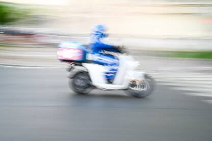Čovjek se brzo kreće na motociklu na ulici, mutna fotografija. Vožnja motorom po gradu. Vozač motocikla.