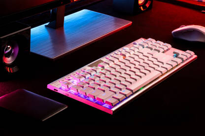 Tastatura na radnom stolu iymedju monitora, miša,zvučnika i hard diska obasijana led svijetlima