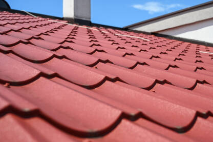 Crveni metalni crijep na krovu kuće. Krov od limova.