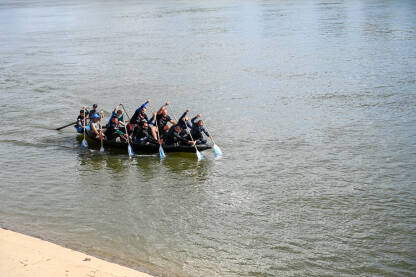 Ljudi treniraju u čamcu na rijeci. Grupa ljudi vesla. Sport i rekreacija.
