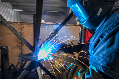 Varioc vari u tvornici. Industrijski radnik zavaruje metal u tvornici.