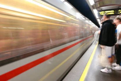 Zamućena fotografija putnika na podzemnoj železničkoj stanici. Voz se brzo kreće. Željeznica. Javni prijevoz u gradu.