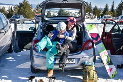 Djevojke se spremaju za ski stazu. Oblačenje ski opreme na parkingu u gepeku. Skijalište Kupres.