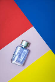 Parfem - staklena boca parfema na reklamnoj višebojnoj podlozi