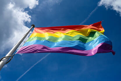 LGBTIQ zastava vijori se na vjetru na jarbolu u gradu. Simbol LGBT zajednice kao društvenog pokreta. Simbol lezbijki, homoseksualaca, biseksualaca, transrodnih osoba