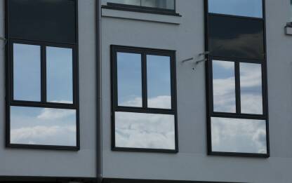 Prozori zgrade na cijim staklima se vide oblaci i plavo nebo