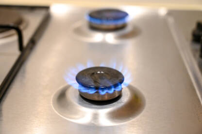 Plinski šporet u kuhinji. Plavi plamen na plinskom štednjaku u kući. Krupni plan zapaljene vatre na plinskom šporetu.
​