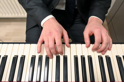 Čovjek svira klavir. Ruke muzičara. Električni piano. Sviranje muzičkog instrumenta u crkvi. Pijanist za klavijaturom.