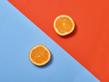 Dvije polovice narandže na kombinaciji plave i crvene pozadine -Koncept