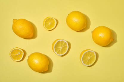Pogled odozgo na limun, s polovicama i cijelim zrelim limunima na žutoj pozadini