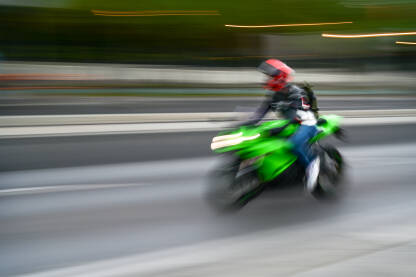 Zamagljeni čovjek se brzo kreće na motociklu ulicom. Vožnja motorom po gradu. Vozač motocikla.