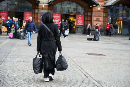 Žena sa torbama ide na željezničku stanicu. Osoba sa prtljagom. Putovanje.