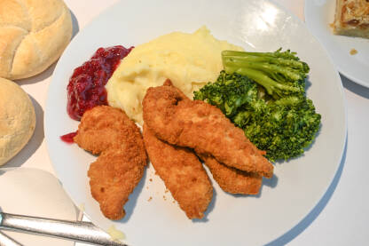 Pohovana piletina, pire krompir, povrće i džem. Ručak serviran na stolu u restoranu.