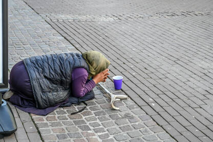Žena prosi na ulici. Siromašna beskućnica prosi novac u gradu. Društveni problem.