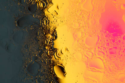 Apstraktna fotografja kapljica ulja i vode na podlozi sa toplim neonskim svjetlom u gradaciji boja. Crvena, pink, narandžasta, žuta, siva i crna. Makro, macro, podloga, pozadina, banner, template.