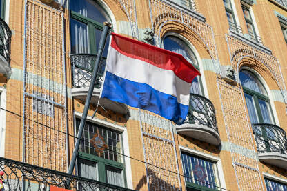 Zastava Kraljevine Nizozemske. Crvena, bijela i plava boja na zastavi Holandije. Zastava Holandije na stubu zgrade u centru grada.