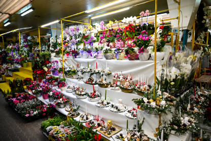 Cvijeće na prodaju na lokalnoj pijaci. Cvjećara s buketima, cvijećem i svijećama. Štand na pijaci koji prodaje cvijeće i ukrase.