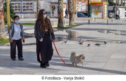 Djevojka sa maskom na licu šeta psa na ulicama Drača, Albanija. Epidemiološke mjere za suzbijanje virusa korona.