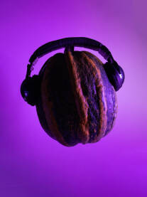 Izdvojena tikva sa crnim slušalicama na neonskoj ljubičastoj podlozi, purple neon background. Kreativni minimalistički koncept - muzika, muzički, muzičar, disco, DJ...