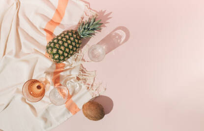 Ljetna scena s ananasom, staklenim čašama, kokosom i peškirom za plažu.