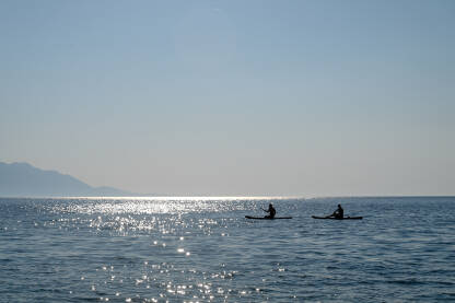 Ljudi veslaju na kajacima u moru. Vožnja kajakom. Rekreacija na vodi. Turisti na odmoru.