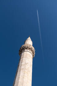 Džamijski minaret naspram plavog neba, avion u letu