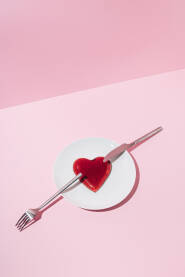 Crveno srce od želea na bijelom tanjuru s vilicom i nožem. Valentinovo.