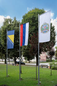 Zastave s grbom Opštine Teslić, Republike Srpske i Bosne i Hercegovine pred zgradom opštine Teslić.