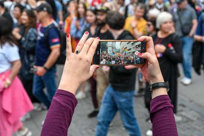 Žena snima događaj mobilnim telefonom. Djevojka mobilnim telefonom snima grupu ljudi na protestu.