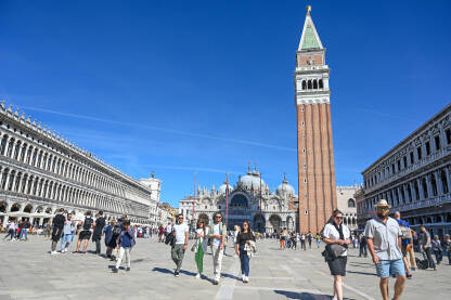 Venecija, Italija: Ljudi šetaju glavnim trgom. Venecija, Italija: Ljudi šetaju glavnim trgom. Piazzetta San Marco. Popularna turistička destinacija. Zvonik, Bazilika svetog Marka i Duždeva palača u centru grada.