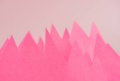 Roze papiri u obliku vrhova planina ispred pozadine.