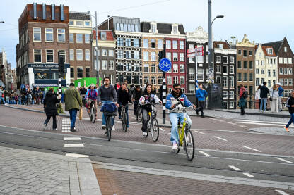 Amsterdam, Nizozemska: Ljudi na biciklima. Biciklisti voze bicikle ulicom. Vožnja biciklom u gradu.