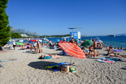 Ljudi uživaju na plaži. Turisti se sunčaju na pješčanoj plaži. Ljetni odmor.