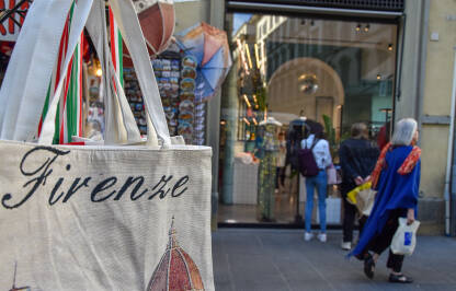 Ceger sa natpisom Firenca, dok je u pozadini butik sa ženskom odjećom. Šoping u Italiji.