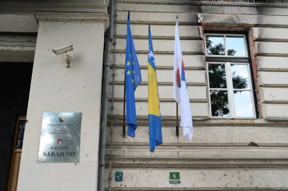 Službena tabla i zastave na zgradi Skupštine Kantona Sarajevo. Tabla s nazivom institucije i zastavama na zgradi Skupštine Kantona Sarajevo.