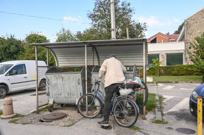 Beskućnik traži hranu u kontejneru. Gladan čovjek kopa po kanti za smeće.