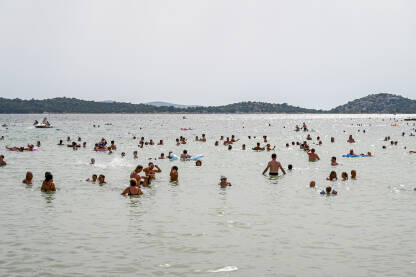 Mnogo kupača u moru na vrhuncu turističke sezone. Ljudi plivaju u moru.