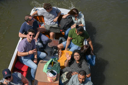 Turisti na brodu istražuju grad. Grupa ljudi na čamcu na rijeci.