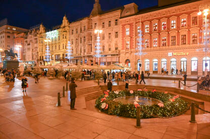 Advent u Zagrebu, Hrvatska. Ukrasi s lampicama na glavnom gradskom trgu. Ljudi se zabavljaju na Adventu na trgu baja Jelačića noću. Fontana Manduševac.