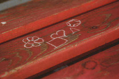 Simboli nacrtani sa kredom ,na crvenoj drvenoj klupi