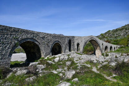 Stari kameni most iznad rijeke. Mesi most na rijeci Kir, Skadar, Albanija. Stari kameni most iznad rijeke. Voda teče ispod mosta. Mesi most na rijeci Kir, Shkoder, Albanija, sagrađen u 18 vijeku. Otomanska arhitektura. Turistička atrakcija.