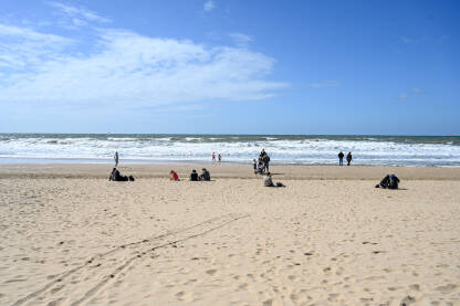 Ljudi na plaži. Obala Sjevernog mora u Hagu. Turisti na pješčanoj plaži.
