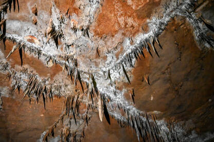 Unutrašnjost pećine ukrašena stalaktitima. Formacije u pećini. Mineralne i kristalne formacije. Speleologija.