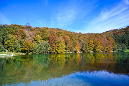 Prekrasan jesenji pejzaž. Drveće uz jezero. Šareno lišće na drveću koje se ogleda u vodi.