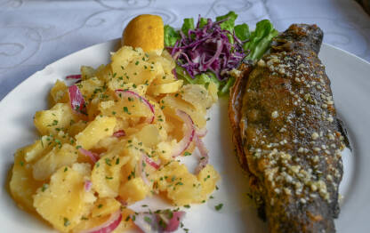 Hrana u vrijeme posta. Pečena riba i krompir salata. Pastrmka sa povrćem, servirana na tanjiru.
